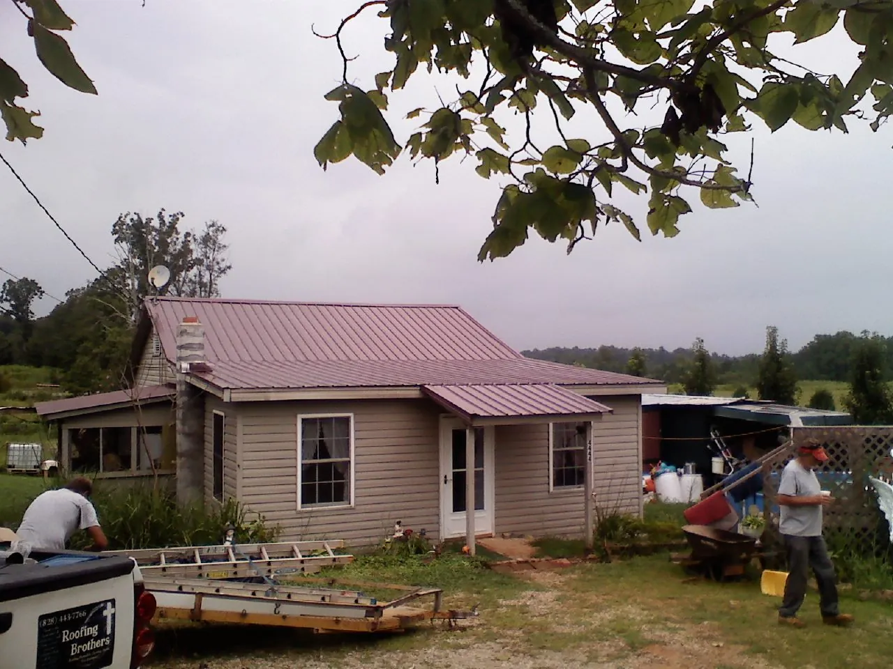 Crew finishing a mauve metal roof on a small farmhouse in Thomaston
