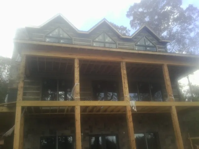 Dormers and porch framing on a large log home under construction — Roof Coating work by our crew in Thomaston