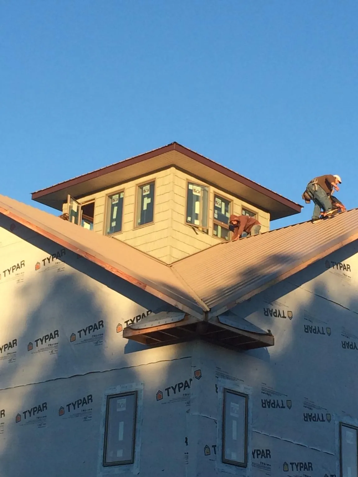 Roofers working around a rooftop cupola on a new metal roof at sunset — Roof Waterproofing in Thomaston by Roofing Brothers